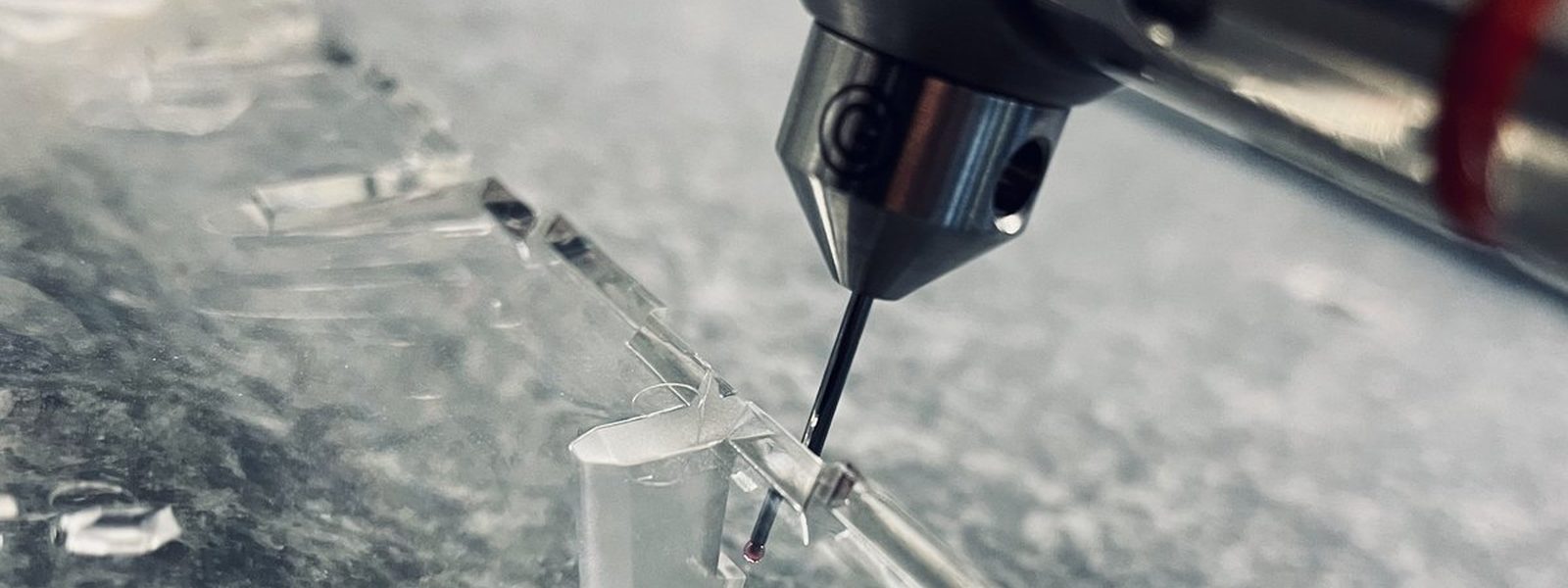 Taktile 3D-Messung an einem transparenten Präzisionsbauteil — Makroaufnahme der Tastspitze beim Antasten
