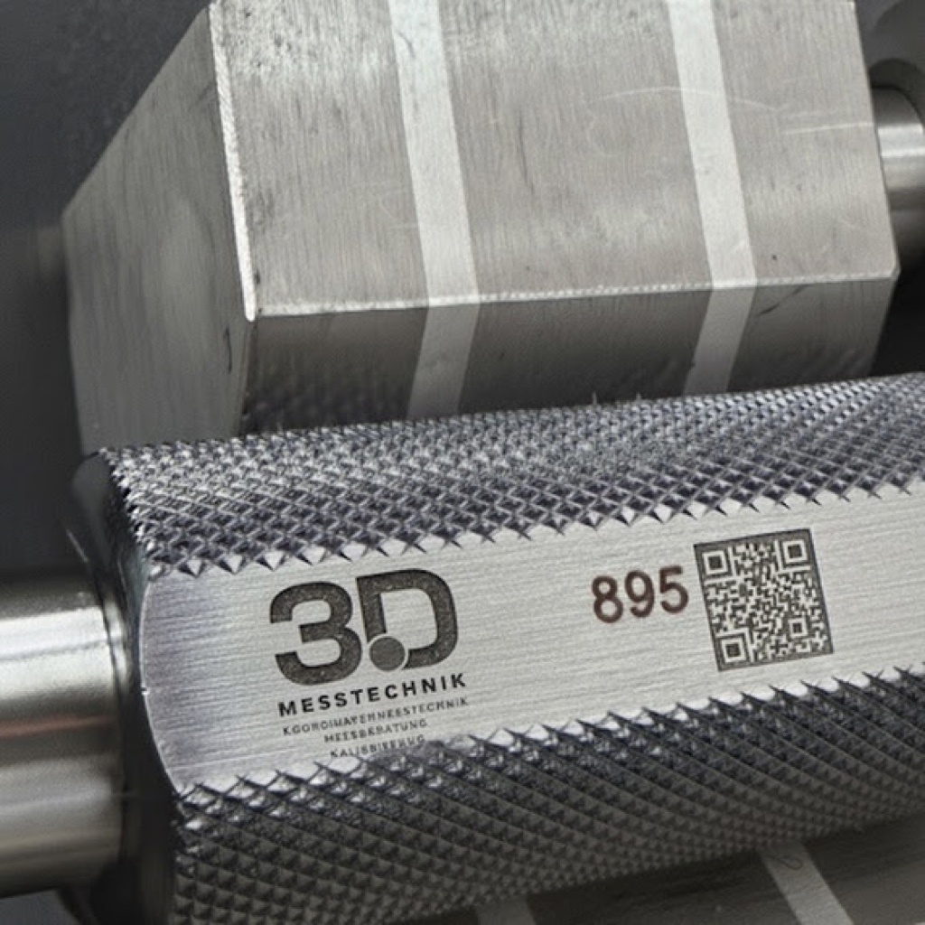 Mess- und Pr&uuml;fmittel mit Lasergravur: 3D-Messtechnik-Firmenlogo, fortlaufende Pr&uuml;fmittel-Nummer 895 und QR-Code zur R&uuml;ckverfolgbarkeit auf einem ger&auml;ndelten Edelstahl-Bauteil.